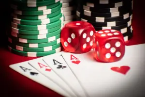 Detail pokerové ruky s kostkami a žetony, symbolizující kasinové hry.